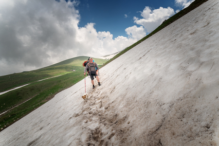 Tourist with a large backpack on a pathway in the mountainsの写真素材