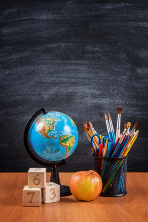 School supplies on the table against the background of the blackboardの写真素材