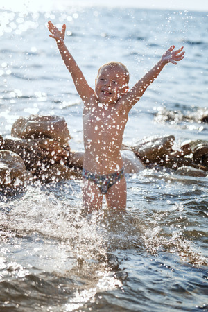 Child playing on the beach splashing waterの写真素材