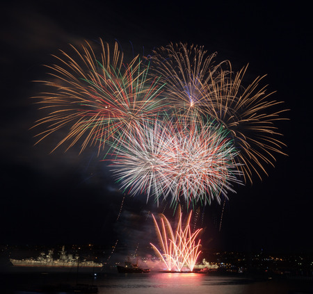 Festive fireworks in the night sky above the waterの写真素材