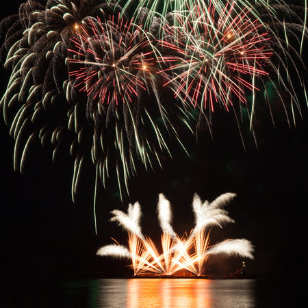Beautiful fireworks in the night sky with reflection on the water