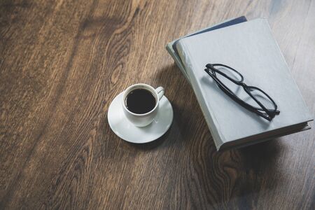 glasses on the books and coffee on deskの写真素材