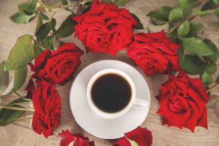 cup of coffee and red roses on deskの写真素材