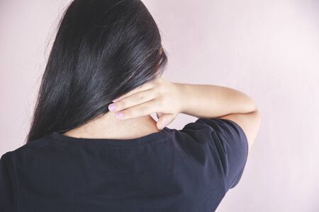 woman hand in  ache neck on pink backgroundの写真素材