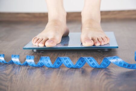 young woman in scales with meters on wooden backgroundの写真素材