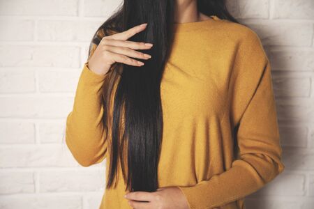 young woman hand in long hair on brick wall backgroundの写真素材