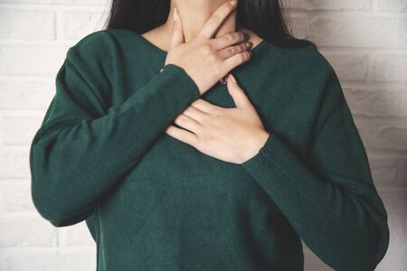 woman hand throat on the brick wall backgroundの写真素材