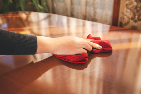 young woman cleaning wooden table background .の写真素材