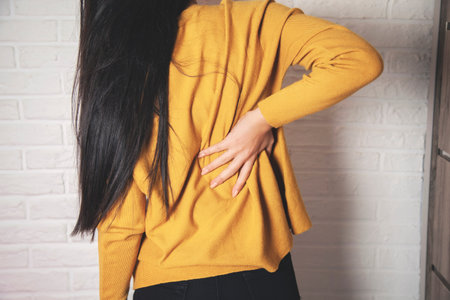woman hand ache back on brick wall background