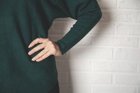 woman hand on hip on brick wall backgroundの写真素材