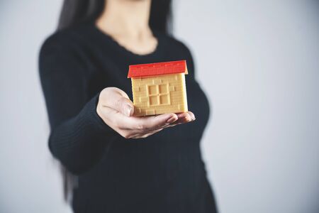 woman hand holding house model on gray backgroundの写真素材