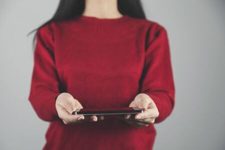 woman hand smart phone on gray wall backgroundの写真素材