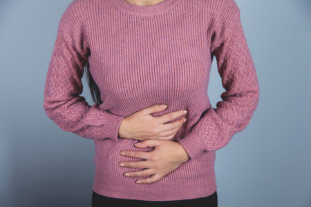 woman hand in ache stomache on gray background