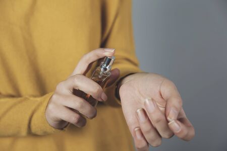 woman hand bottle of perfume on gray backgroundの写真素材
