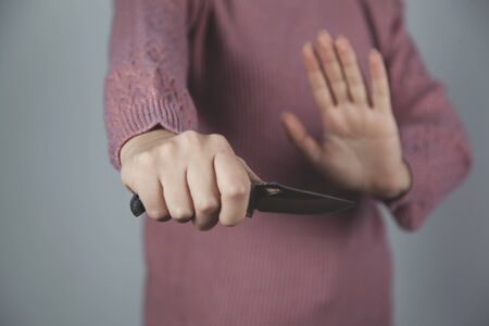 woman hand holding knife on gray backgroundの写真素材