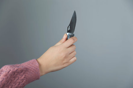 woman hand holding knife on gray background