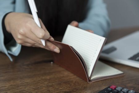 woman hand notepad with computer on deskの写真素材