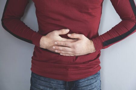 man  hand on ache stomach on gray backgroundの写真素材