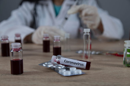 doctor hand syringe on ampoule of coronavirus on table