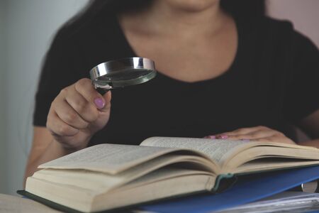 business woman hand pen and magnifier on deskの写真素材