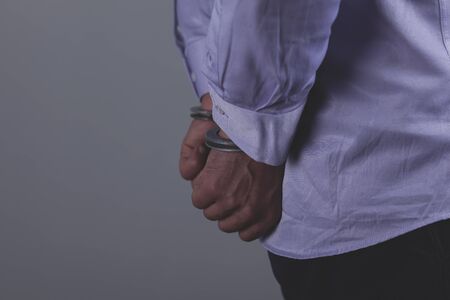 man hand handcuffs in back on the dark backgroundの写真素材