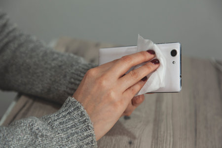 The woman cleans the cell phone with a napkin
