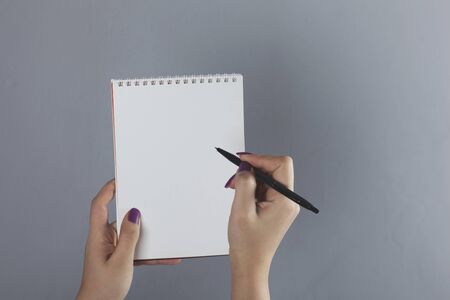 woman hand holding pen and notepad on gray backgroundの写真素材