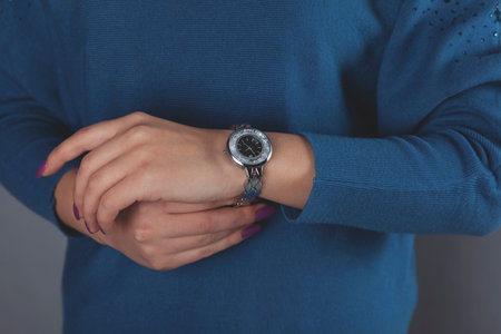 woman hand holding red watch on yellow backgroundの写真素材