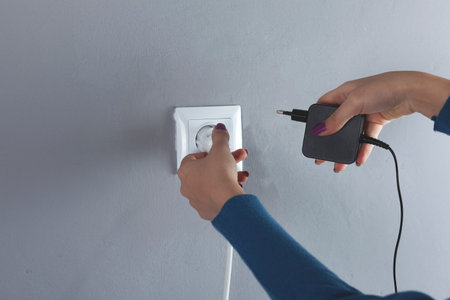 A woman hand pulls a black cord in home