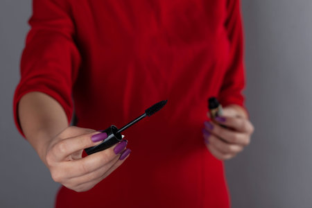 woman hand Mascara on the grey wall backgroundの写真素材