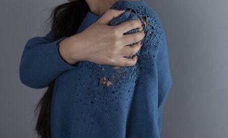 woman ache shoulder on the grey wall backgroundの写真素材