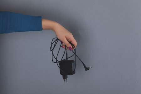 woman hand holding phone charger on gray background