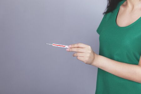 woman handand thermometer on the grey backgroundの写真素材