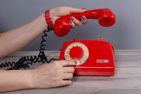 woman hand holding red vintage phone on grey  background
