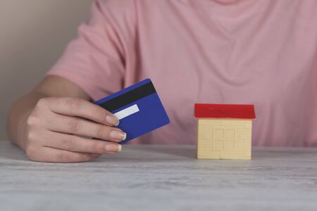 woman hand credit card with house model on tableの写真素材