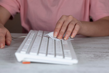Woman cleaning pc keyboard on table