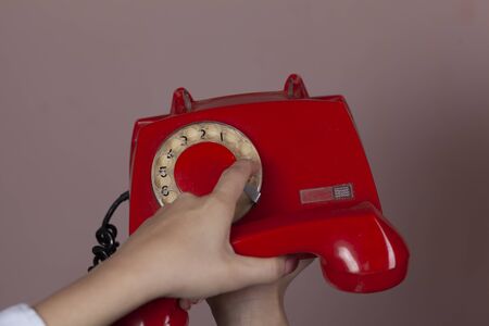 woman hand holding red vintage phone on pink backgroundの写真素材