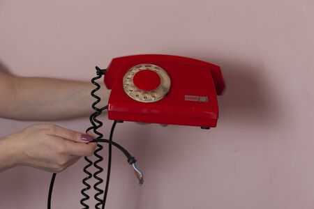 woman hand holding red vintage phone on pink backgroundの写真素材