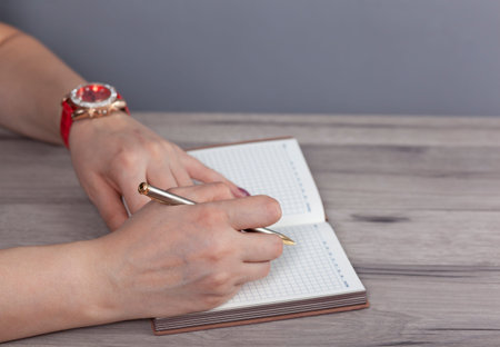 woman hand pen with notepad on the working deskの写真素材
