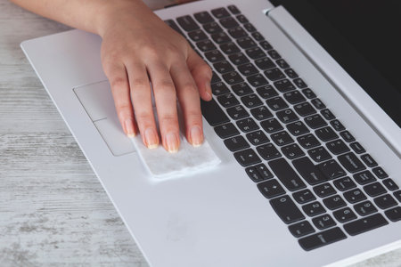 Woman cleaning computer on table