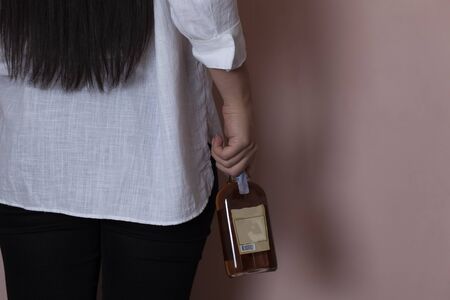 woman hand holding brandy bottle on pink backgroundの写真素材