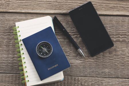 compass on passport on notepad and phone on tableの写真素材