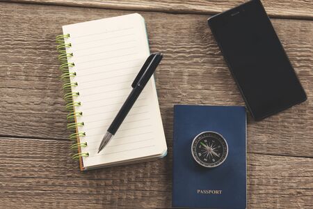 compass on passport on notepad and phone on tableの写真素材