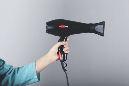 woman hand  hair dryer on the grey wall backgroundの写真素材