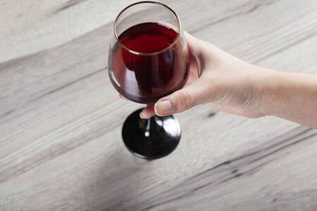 woman hand glass of wine on the desk backgroundの写真素材