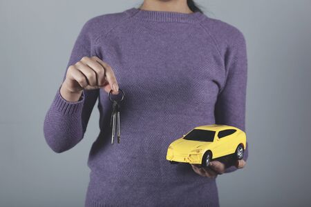 woman hand key and car model on grey backgroundの写真素材