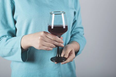 woman hand glass of wine on grey wall backgroundの写真素材