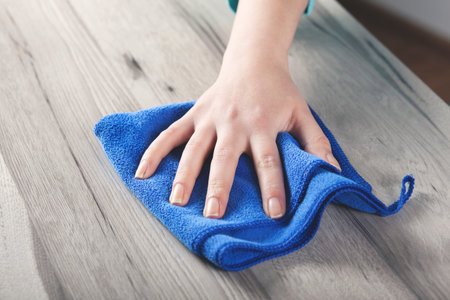 young woman cleaning wooden table background