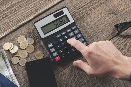 man hand coins with calculator on deskの写真素材