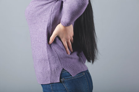 woman ache back on gray background